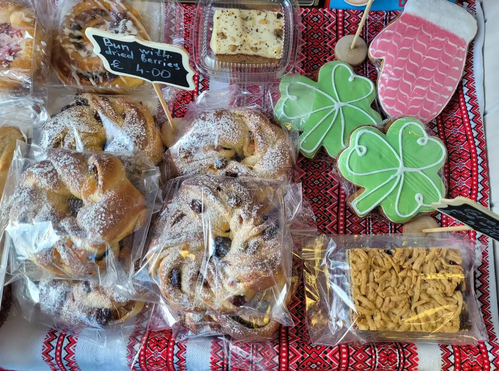 Our market stall flat-lay with packaged buns, shamrock cookies and a handwritten Bun with dried Berries four euro label